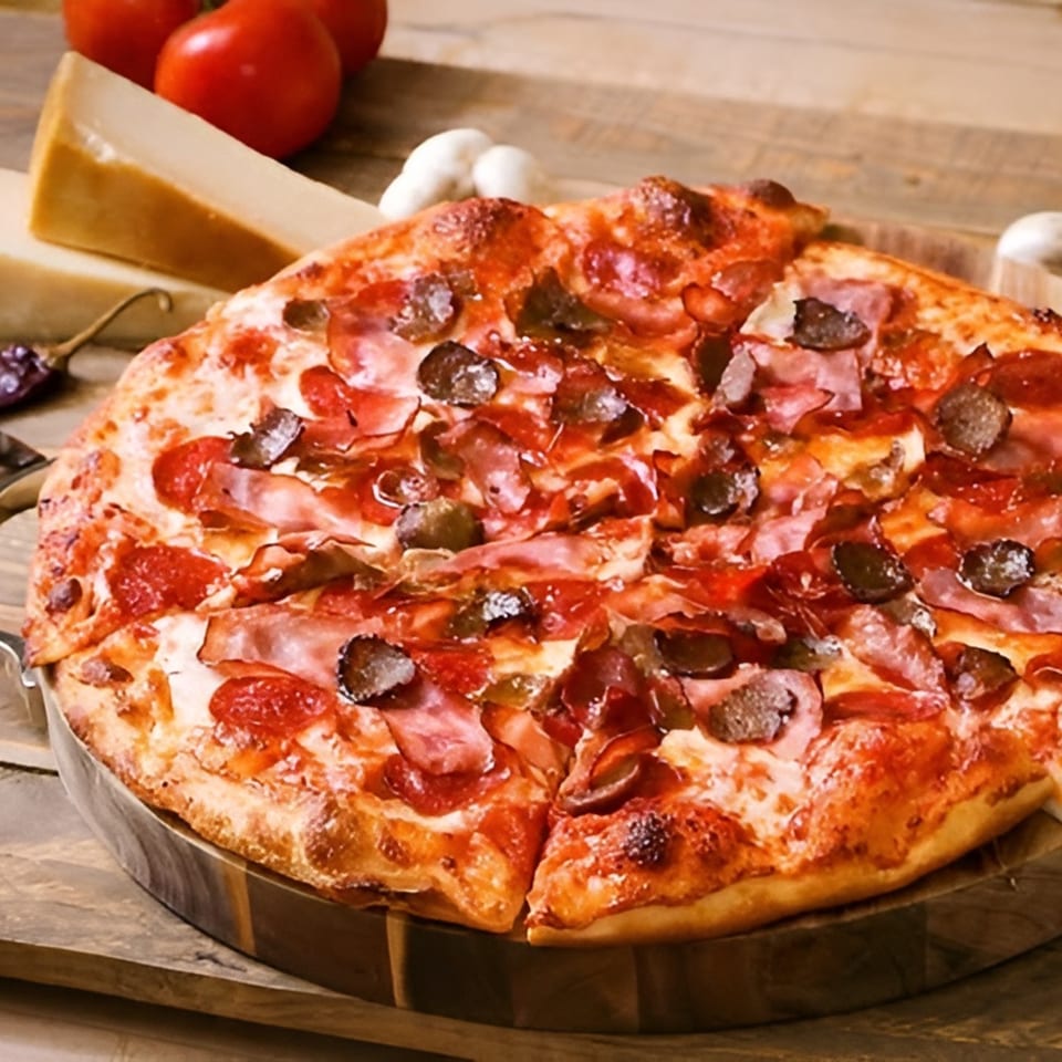 Ameci Pizza & Pasta's pepperoni, ham, and olive pizza on a wooden board with tomatoes and cheese.