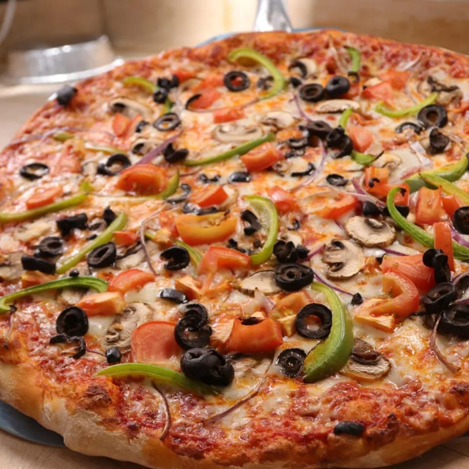 A whole Ameci Pizza & Pasta Canyon Country pizza with bell peppers, olives, mushrooms, and tomatoes.