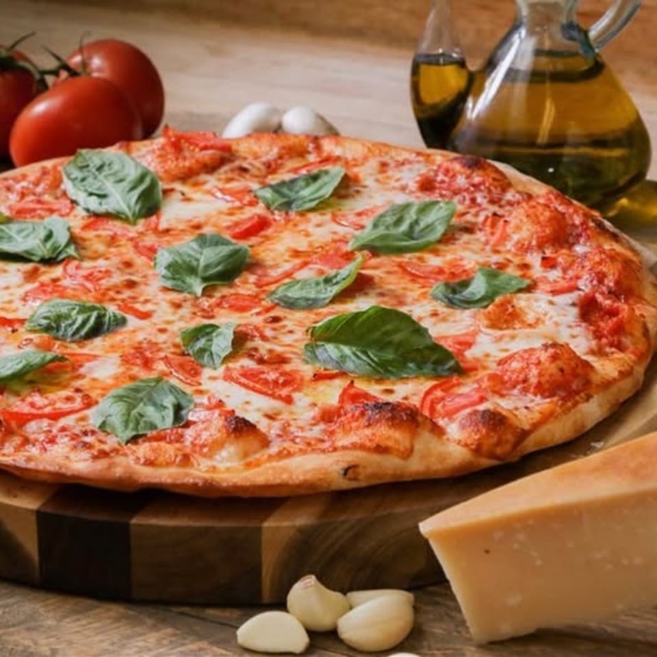 Ameci Pizza & Pasta's Margherita pizza with fresh basil, tomatoes, and mozzarella, surrounded by ingredients.
