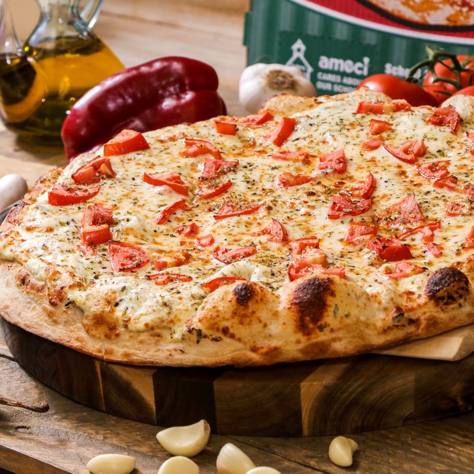 Ameci Pizza & Pasta's white pizza with diced tomatoes and herbs on a wooden board.